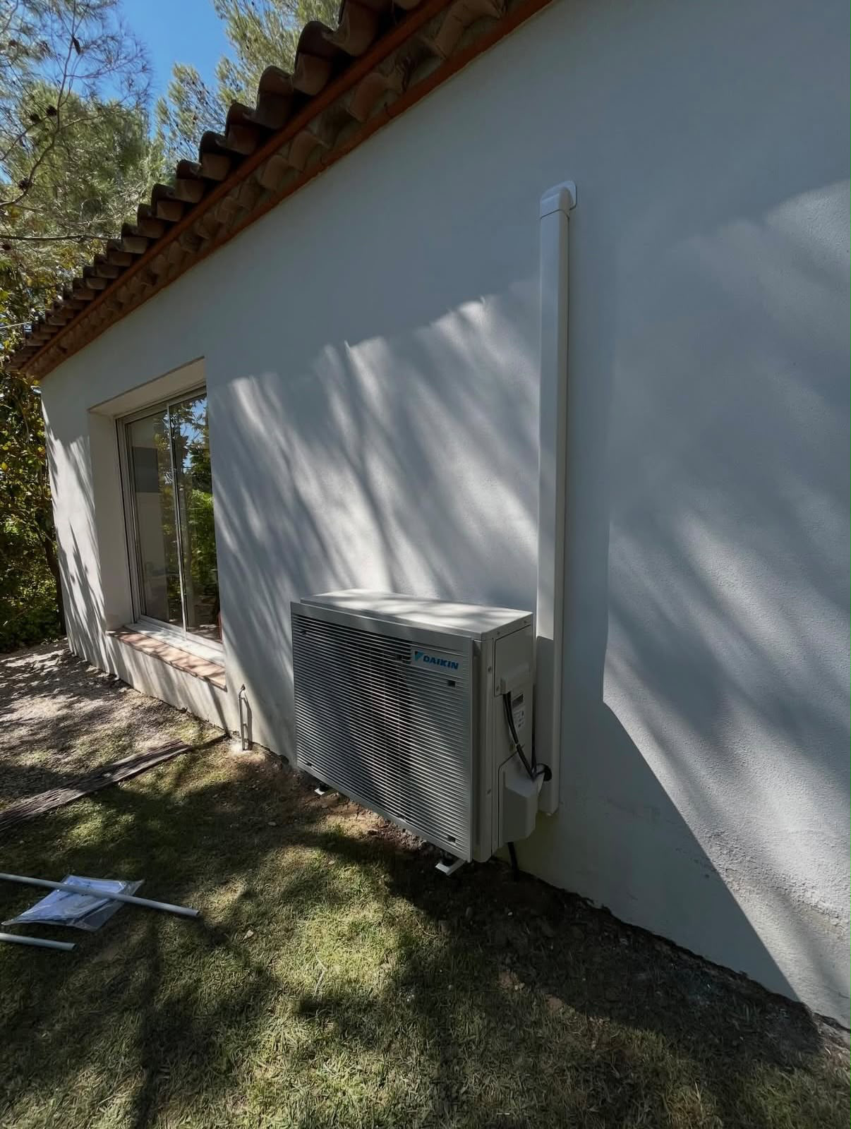 Unité extérieure de pompe à chaleur réversible Daikin installée le long d'une façade de maison