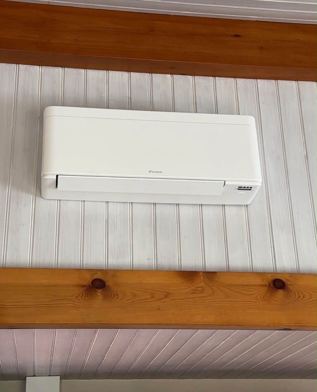 Climatiseur mural Daikin installé sous une charpente en bois