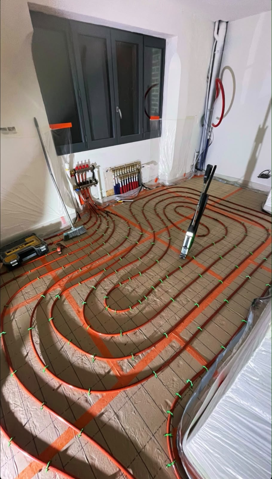 Pose d'un plancher chauffant hydraulique : boucles PER fixées sur dalle et collecteurs, chantier IRH à Reims